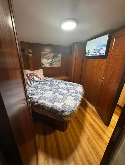  Yacht Photos Pics Cozy bedroom in 1990 Hatteras 45 Convertible yacht with wood paneling and modern TV.