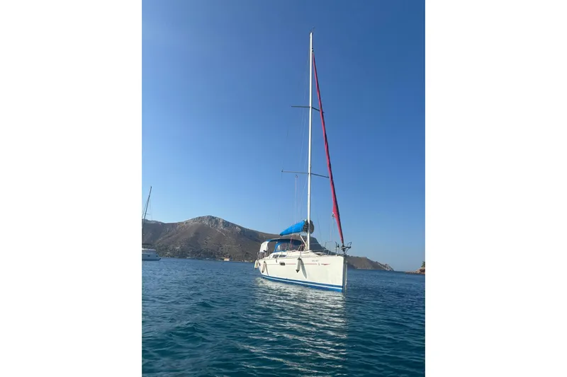  Yacht Photos Pics 2009 Jeanneau Sun Odyssey 39i sailboat on calm blue water with mountainous backdrop.