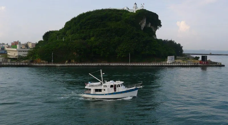 My Lindavia Yacht Photos Pics Kadey-Krogen 44 boat cruising near a lush, green island with a lighthouse, 2012 model.