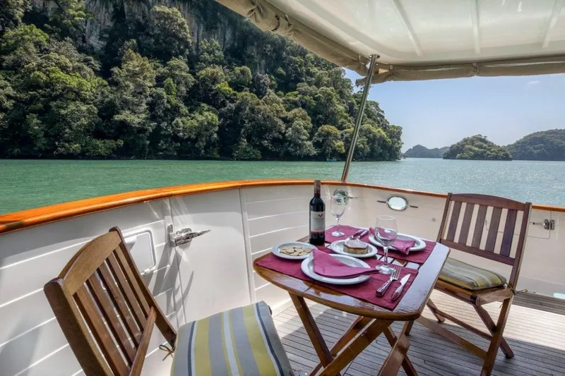 My Lindavia Yacht Photos Pics Luxurious dining setup on a 2012 Kadey-Krogen 44 yacht, overlooking serene waters and lush greenery.