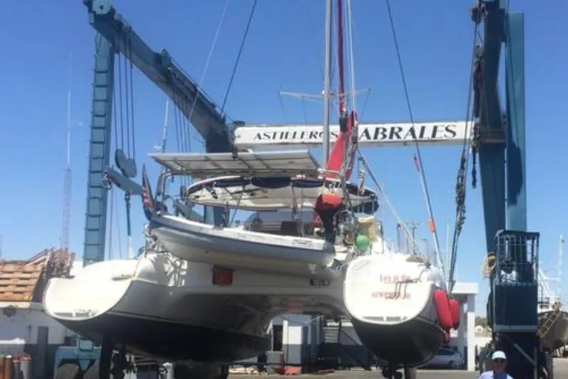 Let It Be Yacht Photos Pics 2003 Fountaine Pajot Bahia catamaran being lifted by a crane at a shipyard.
