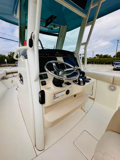 Priced To Sell! Yacht Photos Pics 2020 Boston Whaler 280 Outrage helm with steering wheel and controls, under blue canopy.