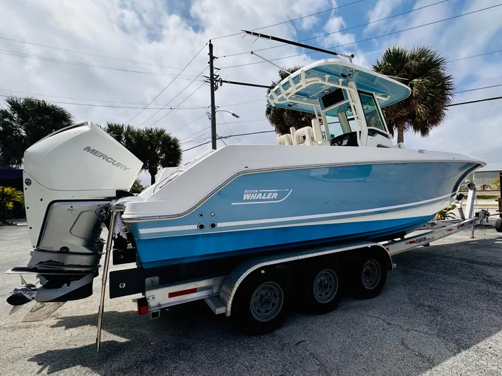 Priced To Sell! Yacht Photos Pics 2020 Boston Whaler 280 Outrage boat on trailer, featuring a sleek blue and white design.