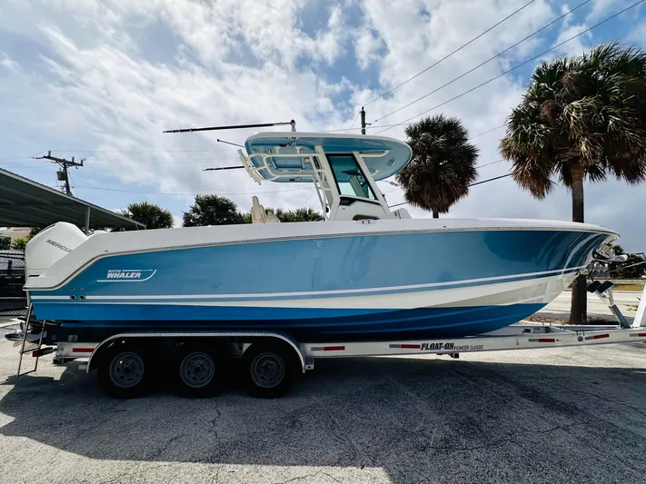 Priced To Sell! Yacht Photos Pics 2020 Boston Whaler 280 Outrage boat on trailer, parked outdoors under cloudy sky.