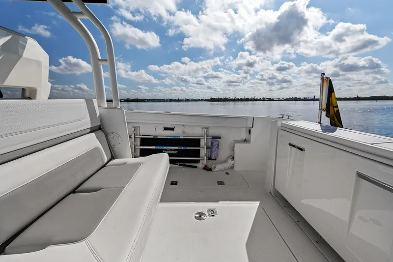  Yacht Photos Pics 2021 Pursuit S 328 Sport boat interior with seating, overlooking calm water and cloudy sky.