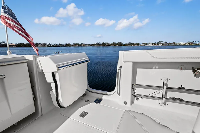  Yacht Photos Pics 2021 Pursuit S 328 Sport boat interior with open deck, American flag, and scenic water view.