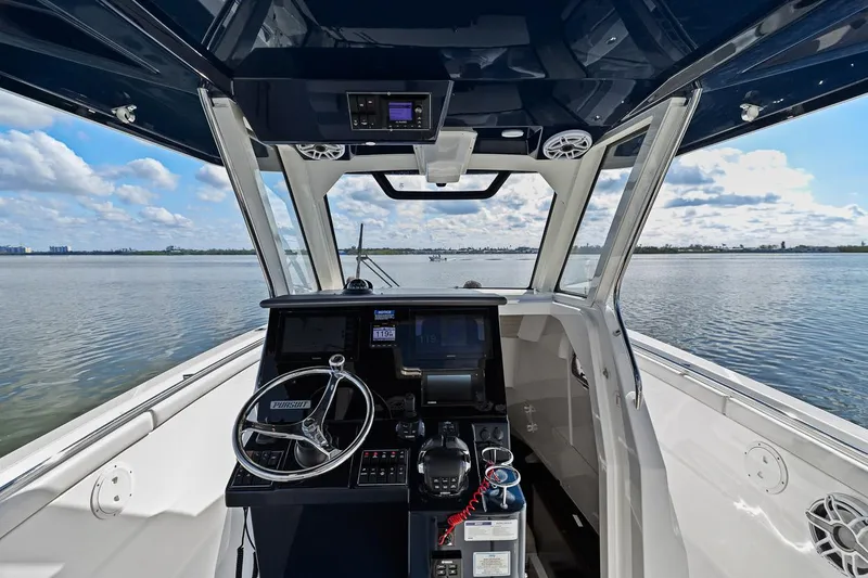  Yacht Photos Pics 2021 Pursuit S 328 Sport boat cockpit with steering wheel and navigation controls.