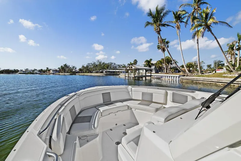  Yacht Photos Pics 2021 Pursuit S 328 Sport boat on a scenic waterfront with palm trees.