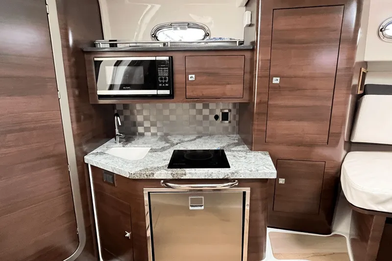  Yacht Photos Pics 2022 Boston Whaler 345 Conquest kitchen with microwave, stove, and wood cabinetry.