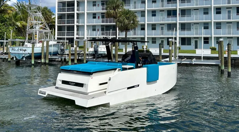  Yacht Photos Pics 2023 De Antonio Yachts D28 Open in marina, modern design, blue cushions, waterfront building backdrop.