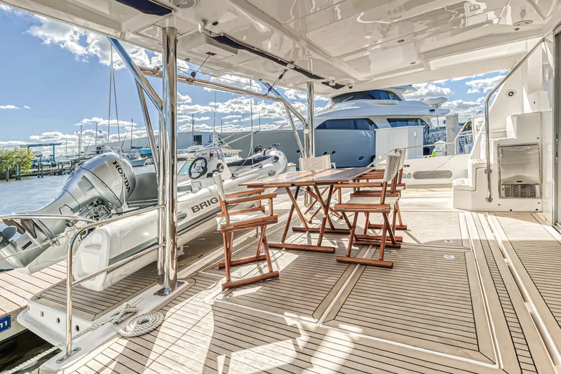 Aquarius Yacht Photos Pics Spacious deck of 2016 Leopard 58 yacht with wooden chairs and table, docked at marina.