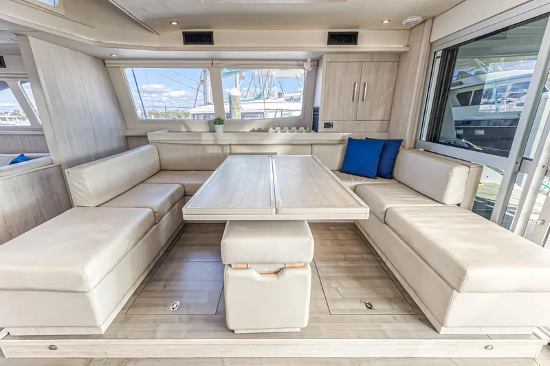 Aquarius Yacht Photos Pics Luxurious interior of 2016 Leopard 58 yacht with beige seating and wooden table.