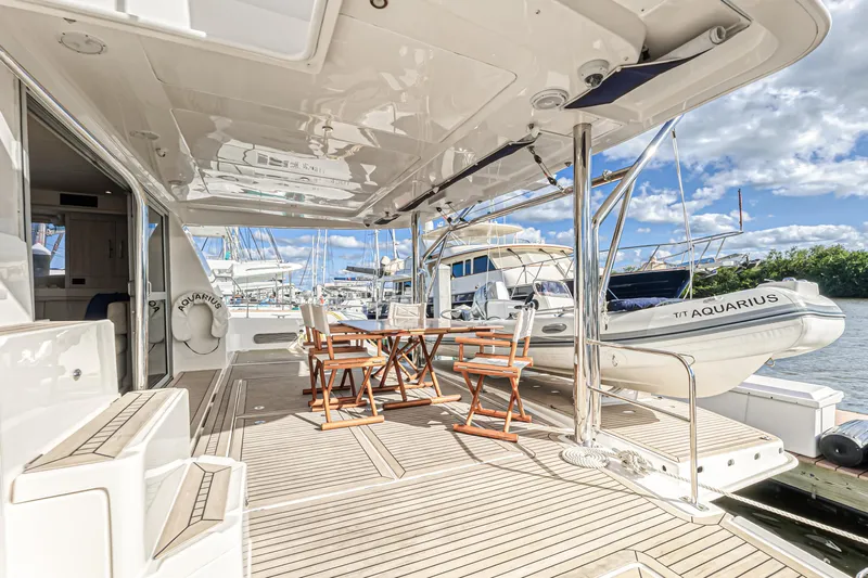 Aquarius Yacht Photos Pics Luxurious 2016 Leopard 58 yacht deck with seating, docked beside other boats under a clear sky.