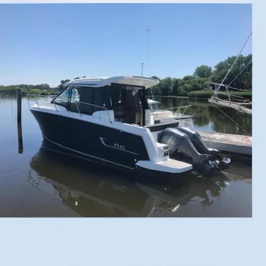  Yacht Photos Pics 2021 Jeanneau NC 895 boat docked on a sunny day, featuring sleek design and outboard motor.