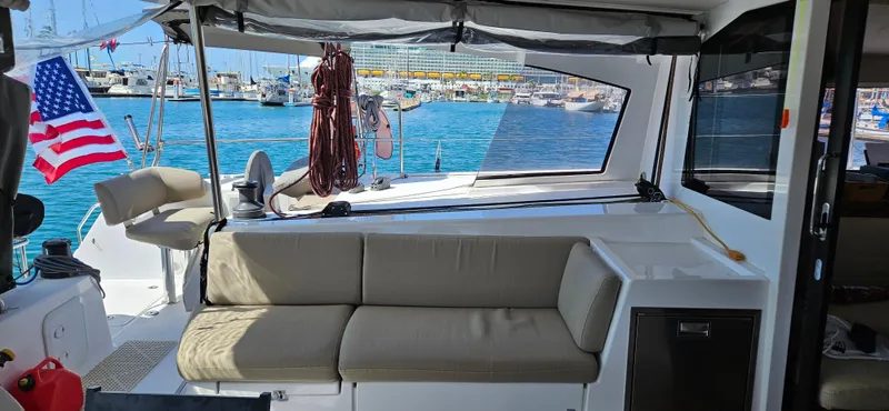 Night Out Yacht Photos Pics 2023 Nautitech 44 Open yacht interior with seating, docked in a marina, American flag visible.