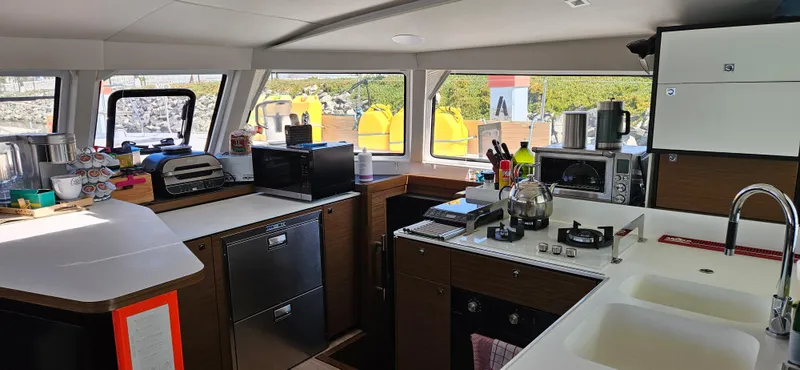 Night Out Yacht Photos Pics Modern kitchen interior of 2023 Nautitech 44 Open catamaran with appliances and ample counter space.