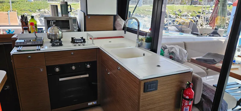 Night Out Yacht Photos Pics Modern kitchen interior of 2023 Nautitech 44 Open catamaran with appliances and seating area.