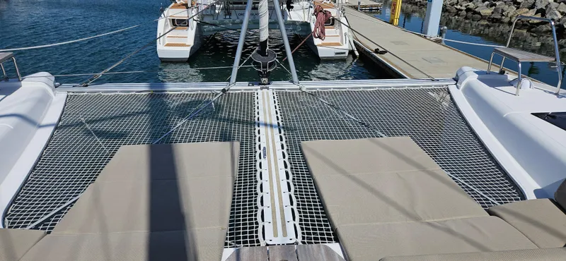 Night Out Yacht Photos Pics 2023 Nautitech 44 Open catamaran with netted deck and sun loungers at marina.