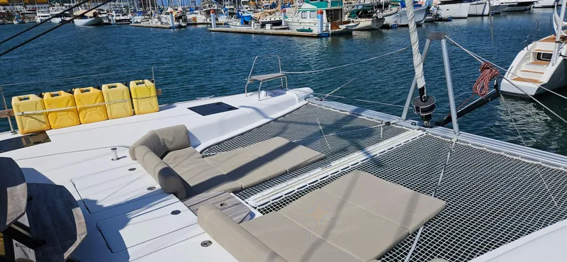 Night Out Yacht Photos Pics 2023 Nautitech 44 Open catamaran with netted deck and lounge chairs in a marina.