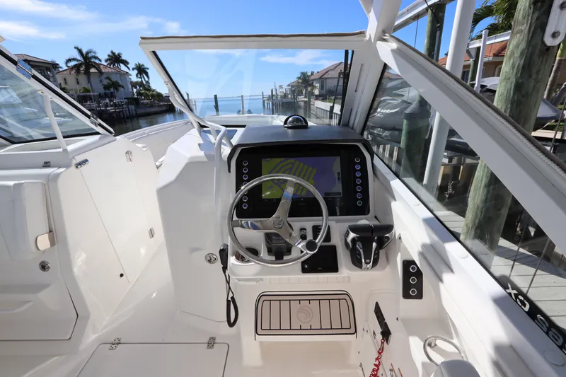  Yacht Photos Pics 2021 Edgewater 262CX Crossover boat cockpit with steering wheel and navigation display.
