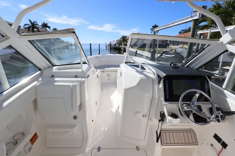  Yacht Photos Pics 2021 Edgewater 262CX Crossover boat interior with steering wheel and dashboard, docked by water.