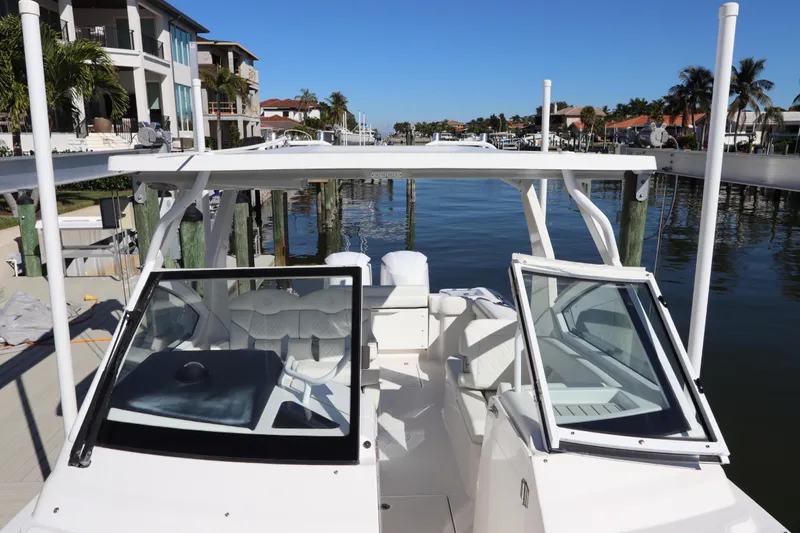  Yacht Photos Pics 2021 Edgewater 262CX Crossover boat docked by waterfront homes under clear blue sky.