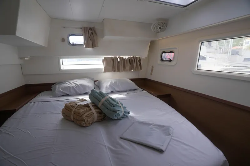 Apres Sail Yacht Photos Pics Cozy cabin interior of 2019 Lagoon 42 catamaran with neatly arranged bed and towels.