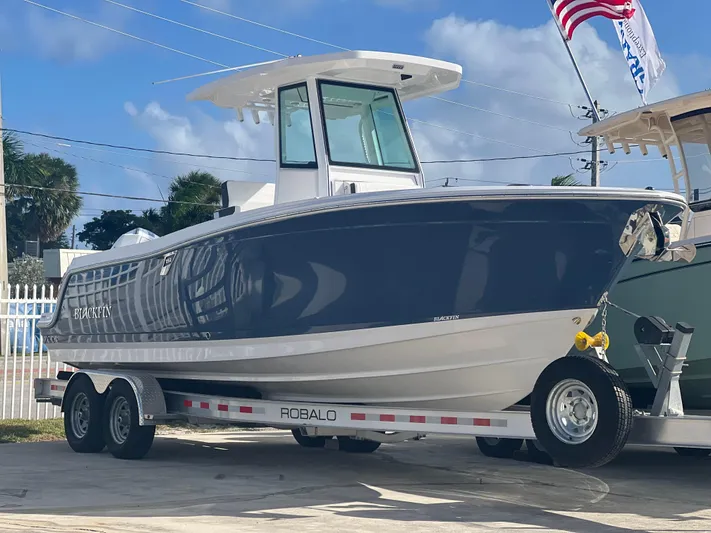 252-449 Yacht Photos Pics 2025 Blackfin 252 CC boat on trailer, displayed outdoors with American flag.
