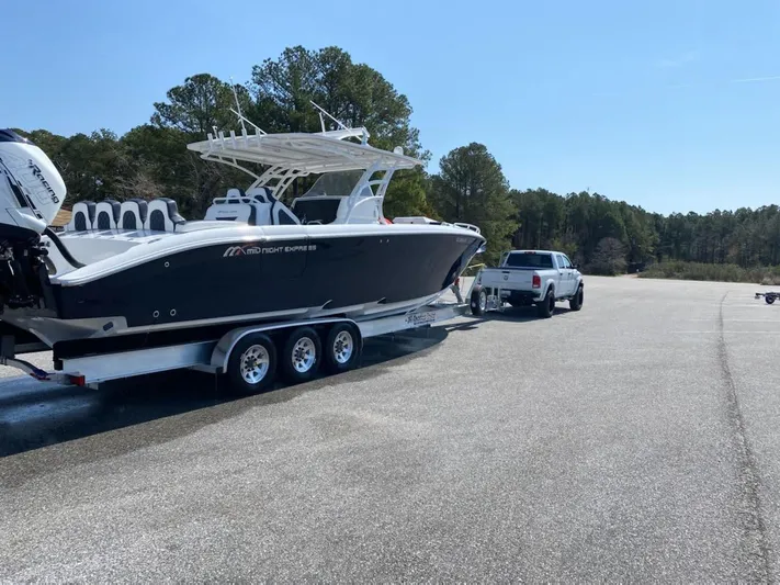  Yacht Photos Pics 2019 Midnight Express 39 Cuddy boat on trailer, towed by a truck in a parking area.