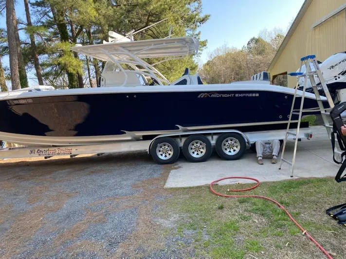  Yacht Photos Pics 2019 Midnight Express 39 Cuddy boat on trailer, parked outdoors near trees and building.