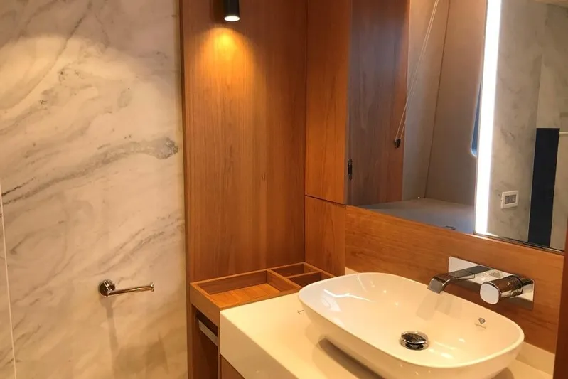 Alexstar Yacht Photos Pics Luxurious bathroom in 2021 Sunseeker Manhattan 68 yacht with modern sink and wood accents.