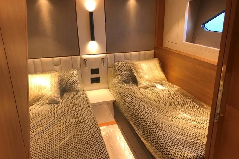 Alexstar Yacht Photos Pics Luxurious twin cabin in 2021 Sunseeker Manhattan 68 yacht, featuring elegant bedding and ambient lighting.