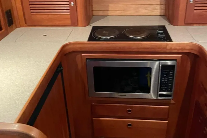 Off-line Yacht Photos Pics 2002 Sabre 36 yacht kitchen with microwave, stovetop, and wooden cabinetry.
