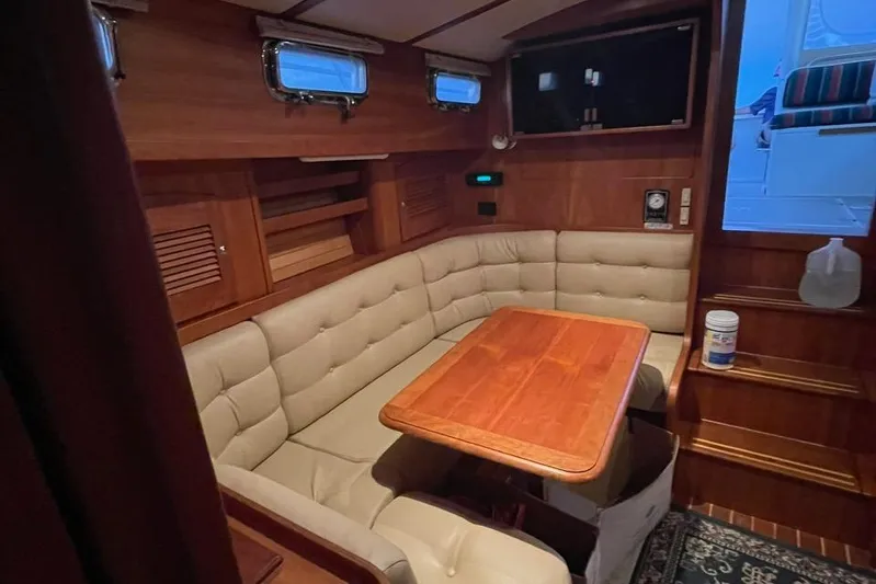 Off-line Yacht Photos Pics Interior of 2002 Sabre 36 yacht with cozy seating and wooden table.