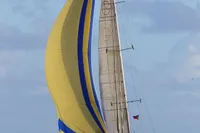 Sailing yacht Devonport Challenge 67, 1995, with vibrant yellow and blue spinnaker on open sea.