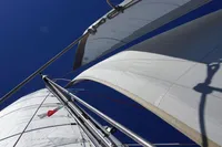 Sails of a 1995 Devonport Challenge 67 yacht against a clear blue sky.