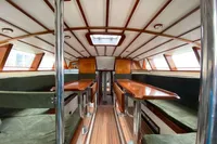 Interior of 1995 Devonport Challenge 67 yacht with wooden tables and green seating.