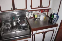 Compact kitchen area in a 1995 Devonport Challenge 67 yacht with stove and storage cabinets.