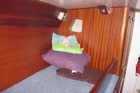 Cozy cabin interior of 1995 Devonport Challenge 67 yacht with wooden paneling and bedding.