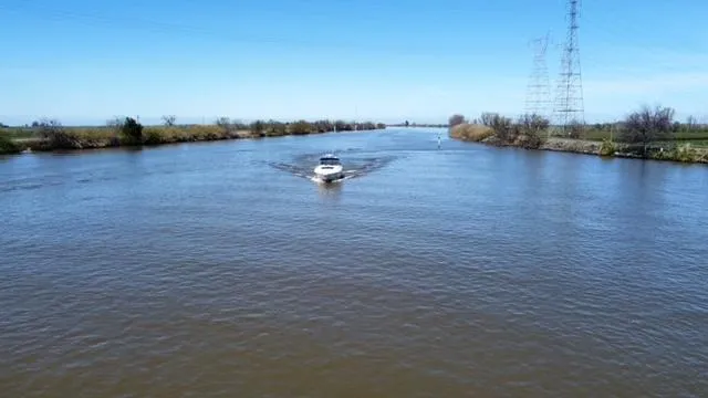  Yacht Photos Pics 2001 Sea Ray 460 Sundancer cruising on a wide river under a clear blue sky.