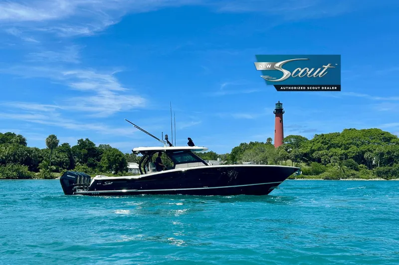 Yacht Photos Pics 2025 Scout 400 LXF boat cruising near a lighthouse on a sunny day.