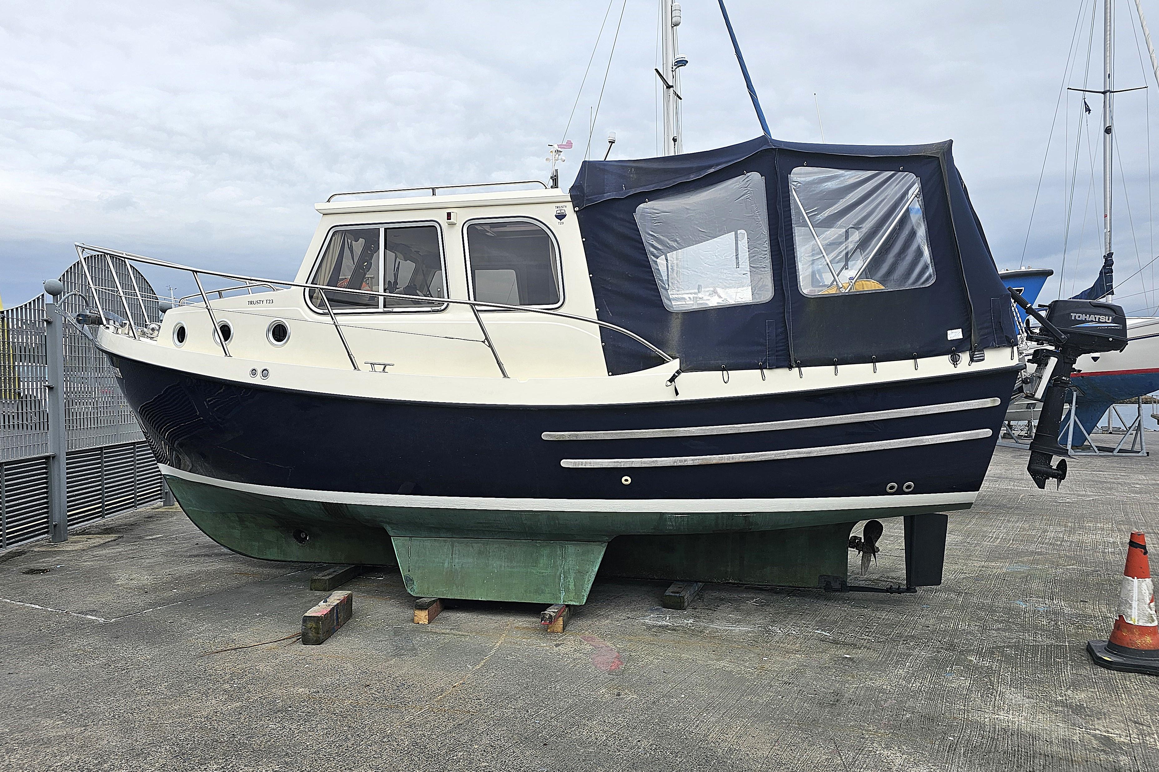 Trusty T23 boat from 2009 on dry dock, featuring a blue and white exterior.