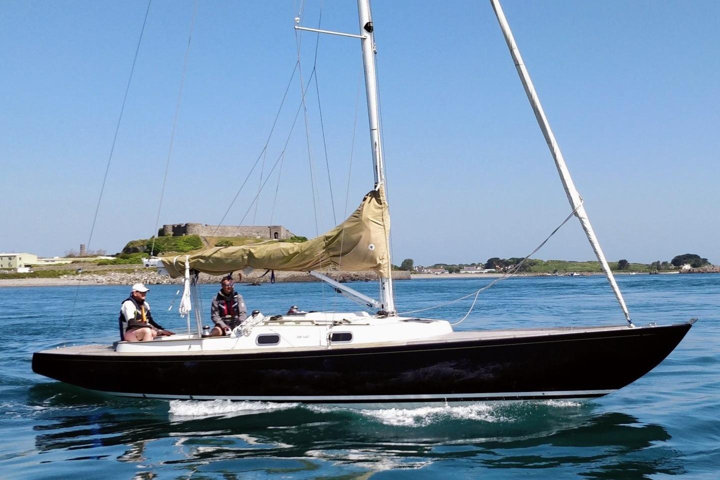 2013 Rustler 33 sailboat on calm waters with two people aboard.