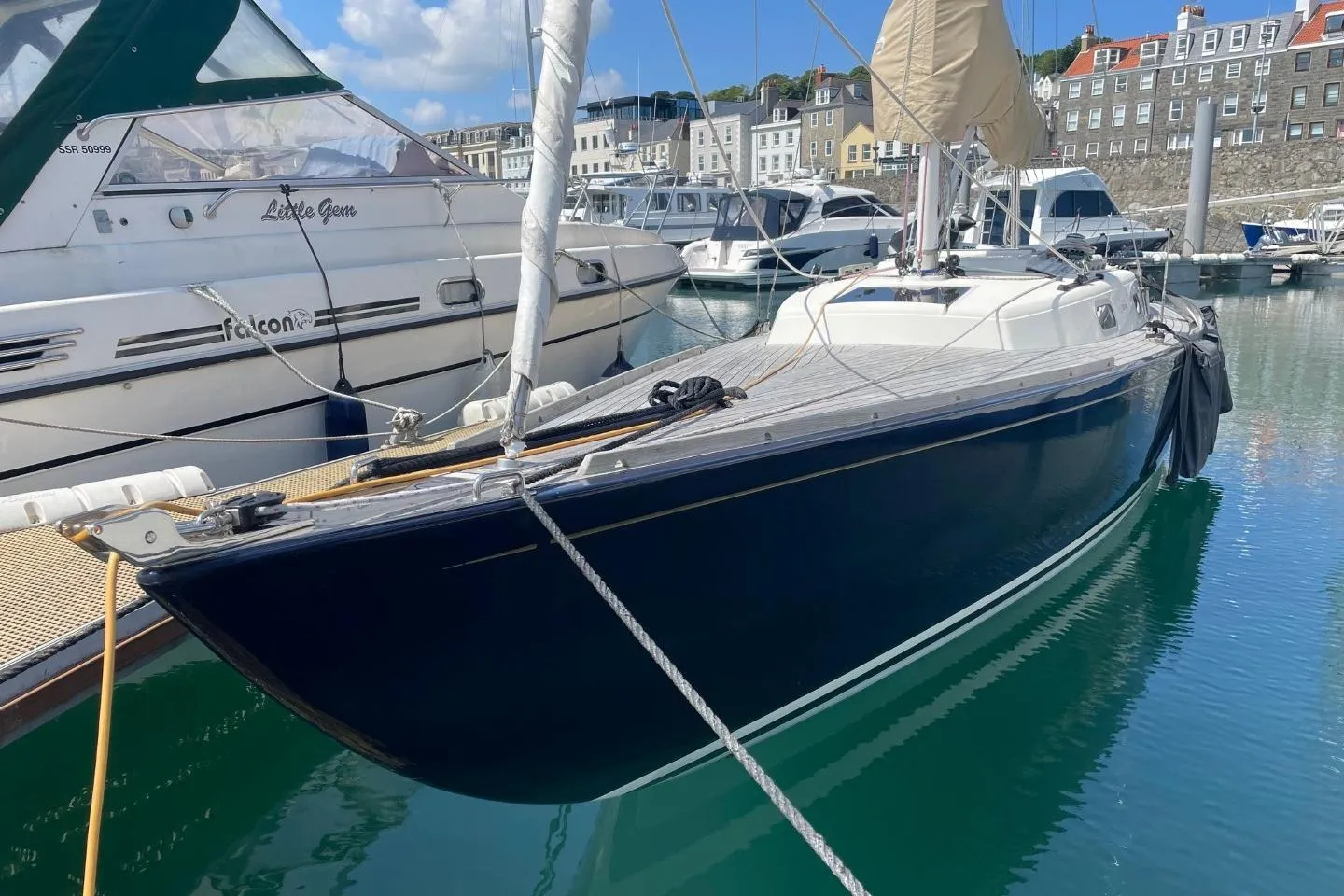 Sailboat Rustler 33, 2013 model, docked in a marina with clear blue water.