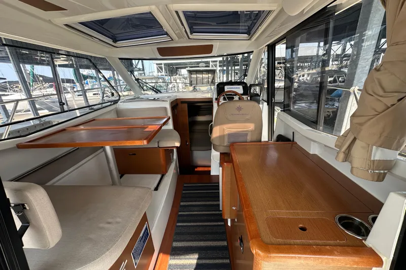 Makai Yacht Photos Pics Interior of 2016 Jeanneau Merry Fisher 855 boat, featuring seating and wooden tables.