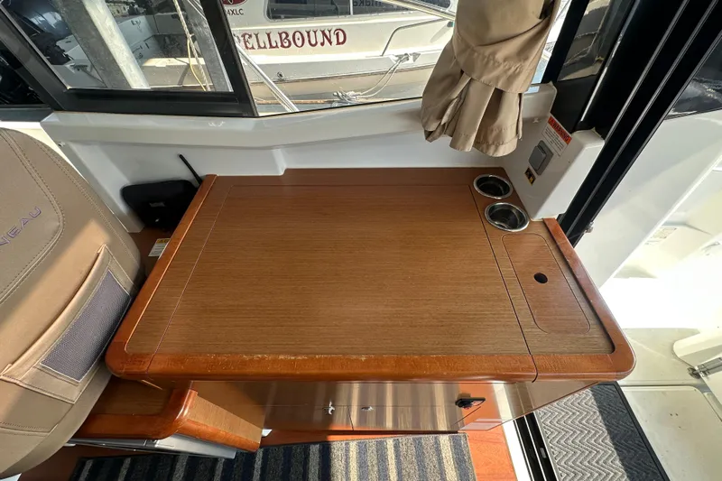 Makai Yacht Photos Pics Interior of 2016 Jeanneau Merry Fisher 855 with wooden table and cup holders.