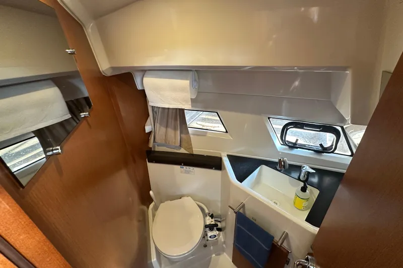 Makai Yacht Photos Pics Compact bathroom in 2016 Jeanneau Merry Fisher 855 boat, featuring toilet, sink, and window.
