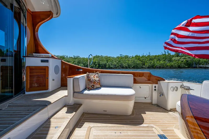 Vera North Yacht Photos Pics 2021 Hinckley Talaria 55 Flybridge MKII yacht deck with seating, wooden accents, and American flag.