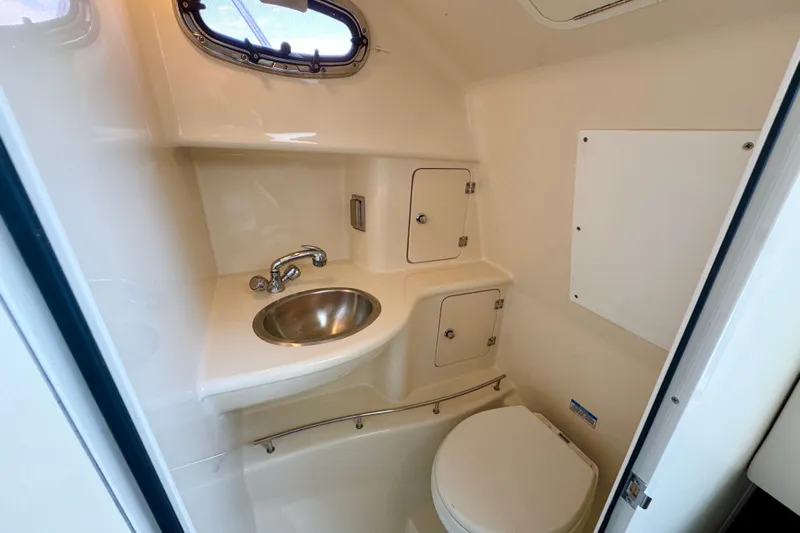 Turn Key Yacht Photos Pics 2006 Boston Whaler 285 Conquest boat bathroom with sink, toilet, and storage cabinets.