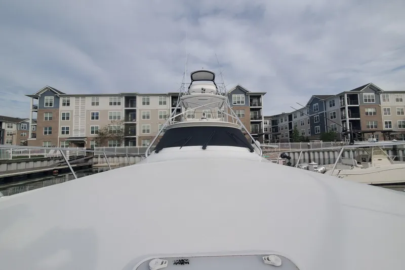 Salty Soul Yacht Photos Pics 2023 Viking 48 Sport Tower yacht docked near modern apartments under cloudy sky.